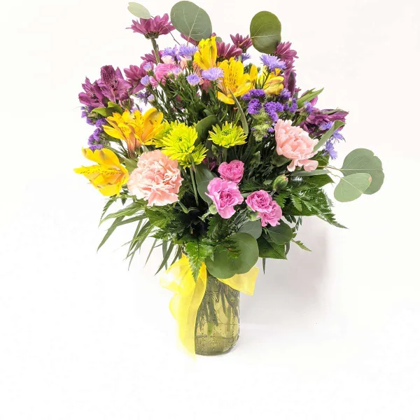 A vibrant mixed bouquet of yellow, pink, and purple flowers arranged in a glass vase.