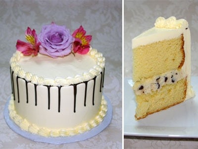 A white frosted cake decorated with purple and pink flowers, shown next to a slice of the cake revealing its layers.