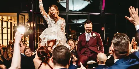A bride and groom dancing at a wedding reception surrounded by guests.
