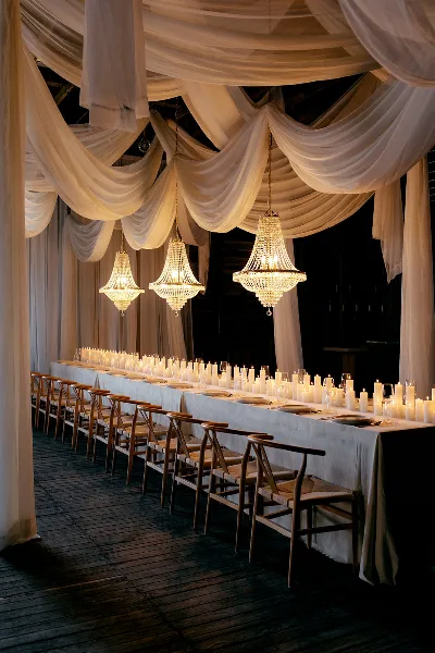 Elegant wedding reception table setting with white drapery and chandeliers