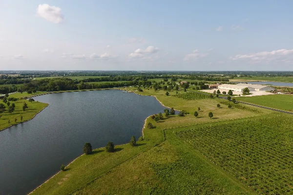 Aerial view of the Bourgmont Winery estate featuring vineyard rows, a large pond, and the main winery buildings.