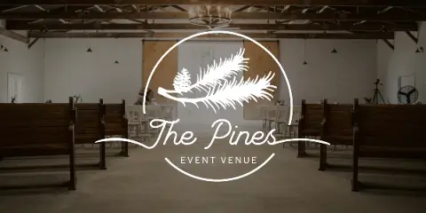 Interior view of a rustic event venue with wooden pews and exposed ceiling beams, overlaid with the 'The Pines Event Venue' logo.