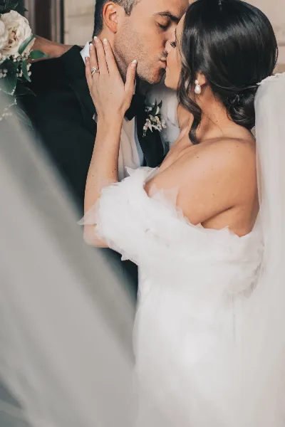 Bride and groom sharing a kiss, with the bride in a white gown and the groom in a black suit.
