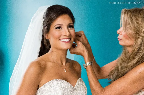 A makeup artist adjusting a bride's hair and makeup during a wedding preparation session.