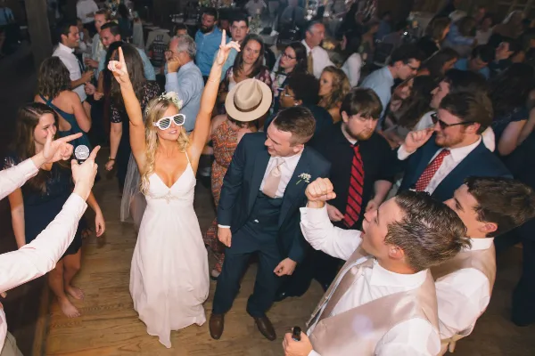 A bride and groom dancing on a crowded wedding dance floor surrounded by guests.
