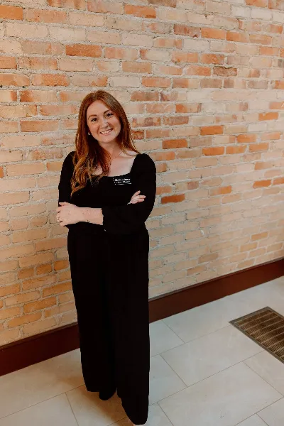Portrait of Jordyn Albritton, founder of Albritton Events, standing in front of a brick wall wearing a black outfit and a business name badge.