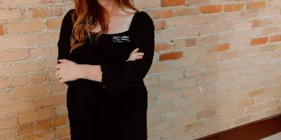 Portrait of Jordyn Albritton, founder of Albritton Events, standing in front of a brick wall wearing a black outfit and a business name badge.