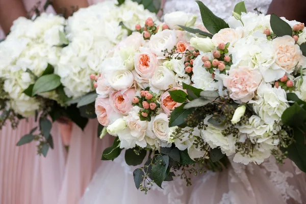 Close-up of a wedding floral arrangement featuring white hydrangeas, blush garden roses, and greenery.