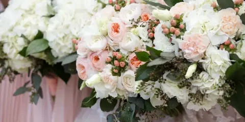 Close-up of a wedding floral arrangement featuring white hydrangeas, blush garden roses, and greenery.