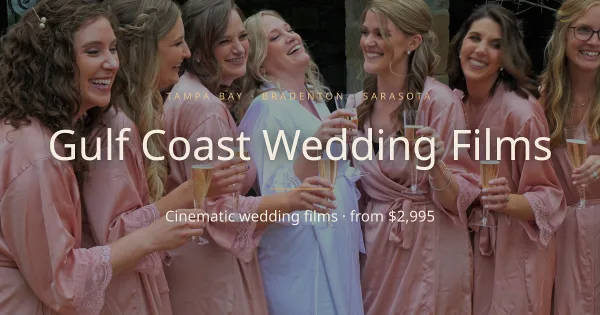 A bride and her bridesmaids in pink robes laughing and holding champagne flutes.