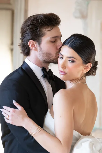 A bride with an elegant updo and professional makeup posing with her groom.