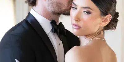 A bride with an elegant updo and professional makeup posing with her groom.