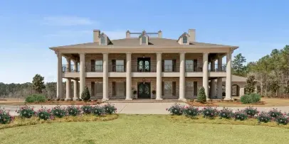 Exterior view of a two-story brick and stucco venue building with a large columned porch and manicured landscaping.
