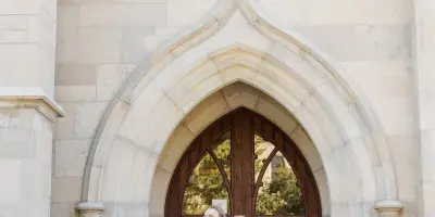 A bride and groom standing together in front of a stone church entrance.