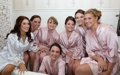 A group of bridesmaids in pink and white robes posing together.