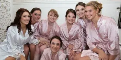 A group of bridesmaids in pink and white robes posing together.