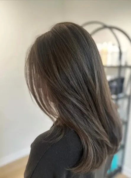 A client with a freshly styled, highlighted bob haircut viewed from the back in a salon.