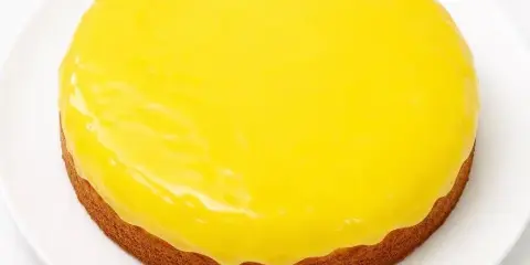A round cake with a smooth yellow glaze on a white plate