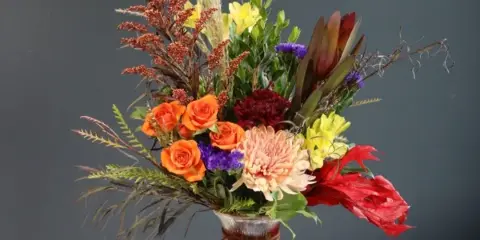 Mixed bouquet in a ribbed glass vase with orange roses and a peach chrysanthemum