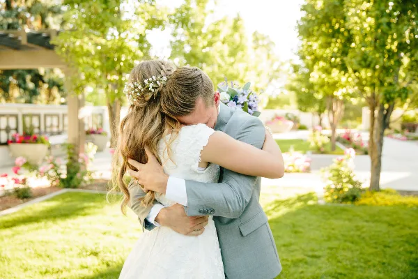 A bride and groom hugging outdoors in a garden setting