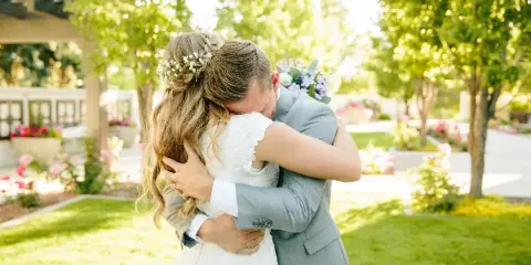 A bride and groom hugging outdoors in a garden setting