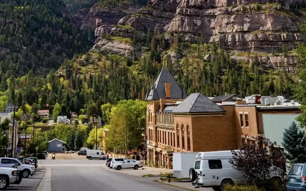Exterior view of the historic Beaumont Hotel in Ouray, Colorado, set against a backdrop of steep, forested mountains.