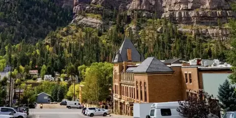 Exterior view of the historic Beaumont Hotel in Ouray, Colorado, set against a backdrop of steep, forested mountains.