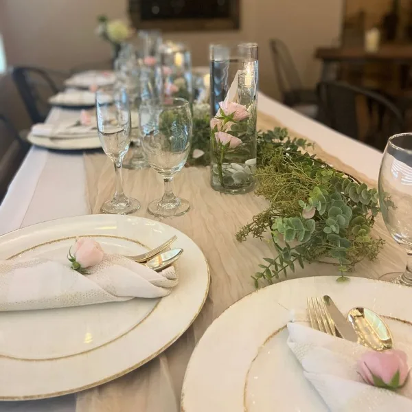 Formal event table setting with white plates, glassware, and floral centerpieces.
