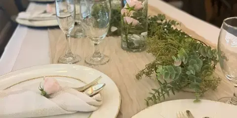 Formal event table setting with white plates, glassware, and floral centerpieces.