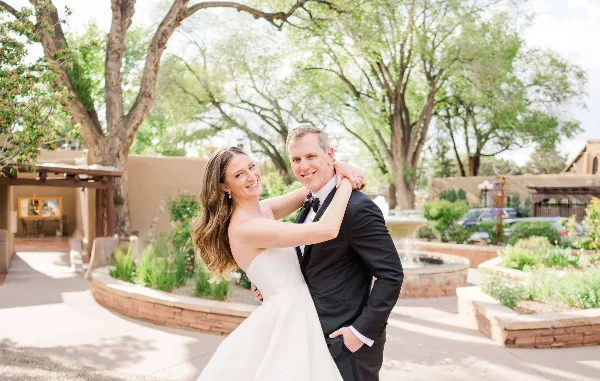 A bride and groom smiling and embracing outdoors in a garden setting.