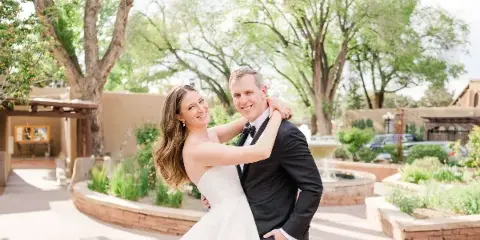 A bride and groom smiling and embracing outdoors in a garden setting.