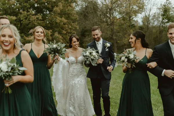 A bride and groom walking with their wedding party in an outdoor setting.
