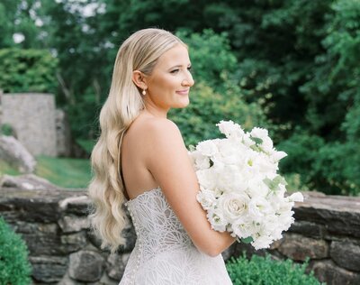 Bride with long wavy blonde hair holding a white bouquet