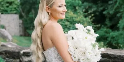 Bride with long wavy blonde hair holding a white bouquet