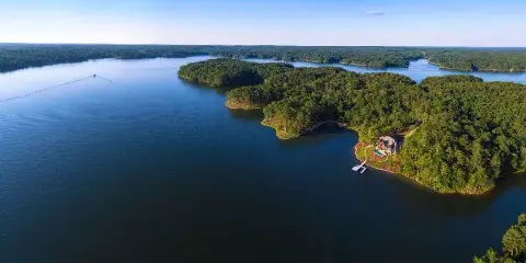 Aerial view of a large lake with forested islands and a waterfront property.