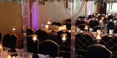 A wedding reception room with tall floral centerpieces, candles, and decorated tables.