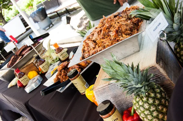 Catering buffet table with pulled pork, BBQ sauces, and fresh produce