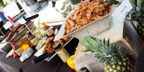 Catering buffet table with pulled pork, BBQ sauces, and fresh produce