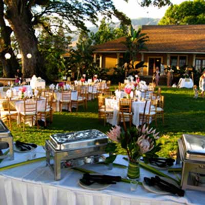 Outdoor catering event featuring buffet chafing dishes and a decorated venue with tables and chairs.