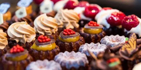 A close-up view of a variety of decorated pastries, including tarts with fruit toppings and cream-filled cakes.