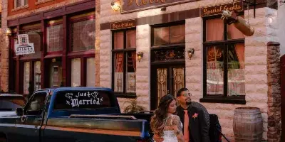 A bride and groom posing in front of The Courtyard venue building in Bisbee, Arizona.