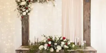 Rustic wedding sweetheart table with floral arrangements and a wood backdrop