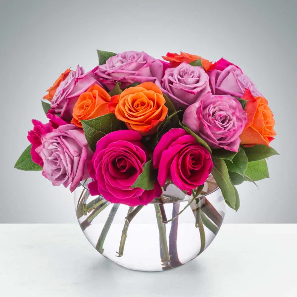 A bouquet of pink, lavender, and orange roses arranged in a clear glass vase.