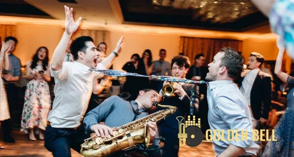 A live band performing at a wedding reception with a saxophone and trumpet, surrounded by dancing guests.