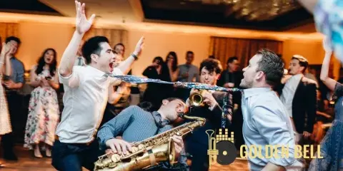 A live band performing at a wedding reception with a saxophone and trumpet, surrounded by dancing guests.