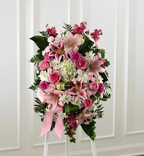 A tall, elegant floral standing spray featuring pink lilies, roses, and hydrangeas on a white stand.