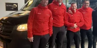 Eagle Mountain Express chauffeurs in red jackets standing next to a black Mercedes-Benz Sprinter van at a Vail Valley resort in winter.