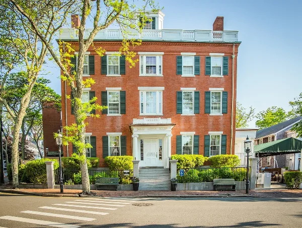 Exterior view of the Jared Coffin House, a historic red brick hotel with white trim and green shutters in Nantucket.