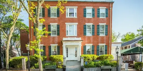 Exterior view of the Jared Coffin House, a historic red brick hotel with white trim and green shutters in Nantucket.