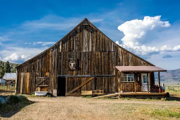 Exterior view of a rustic wooden barn venue with a small attached porch and a blue sky background.